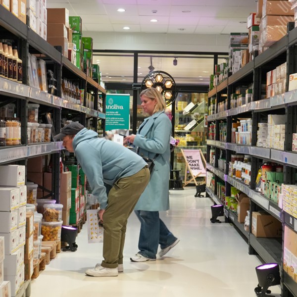 Een breed zicht op een schone, goed verlichte supermarktgang met goedgevulde rekken.
